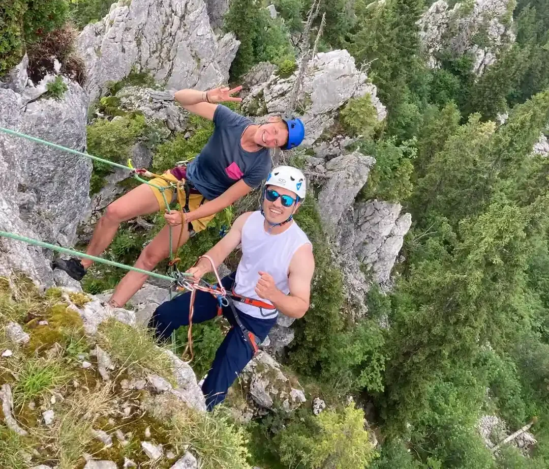 Zwei lachende Personen beim Outdoor-Klettern am Fels in der Natur